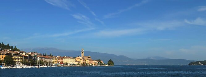 Trip Rom beliebte Urlaubsziele am Gardasee -  Mit einer Fläche von 370 km² ist der Gardasee der größte See Italiens. Es liegt am Fuße der Alpen und erstreckt sich über drei Staaten: Lombardei, Venetien und Trentino. Die maximale Tiefe des Sees beträgt 346 m, er hat eine längliche Form und sein nördliches Ende ist sehr schmal. Dort ist der See von den Bergen der Gruppo di Baldo umgeben. Du trittst aus deinem gemütlichen Hotelzimmer und es begrüßt dich die warme italienische Sonne. Du blickst auf den atemberaubenden Gardasee, der in zahlreichen Blautönen schimmert - von tiefem Dunkelblau bis zu funkelndem Türkis. Majestätische Berge umgeben dich, während die Brise sanft deine Haut streichelt und der Duft von blühenden Zitronenbäumen deine Nase kitzelt. Du schlenderst die malerischen, engen Gassen entlang, vorbei an farbenfrohen, blumengeschmückten Häusern. Vereinzelt unterbricht das fröhliche Lachen der Einheimischen die friedvolle Stille. Du fühlst dich wie in einem Traum, der nicht enden will. Jeder Schritt führt dich zu neuen Entdeckungen und Abenteuern. Du probierst die köstliche italienische Küche mit ihren frischen Zutaten und verführerischen Aromen. Die Sonne geht langsam unter und taucht den Himmel in ein leuchtendes Orange-rot - ein spektakulärer Anblick.